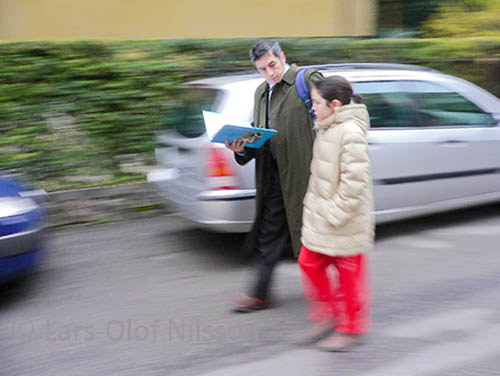 While walking to school a father is checking his daughter's knowledge to see if she has done her homework