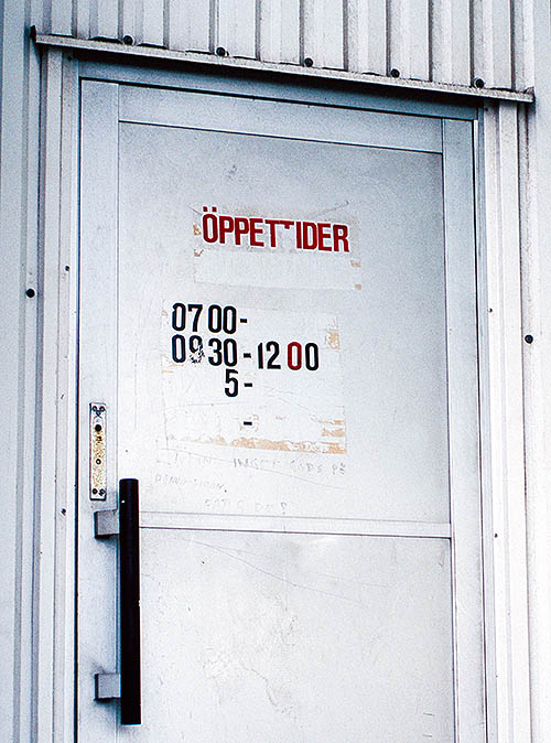 Door with incomplete text showing opening hours.