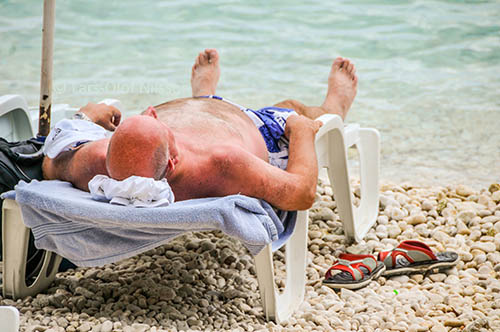 A man lying on a sun chair on a beach.