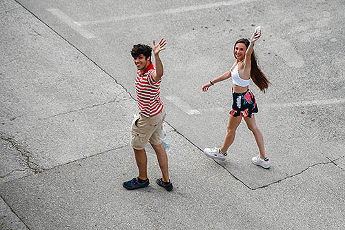 A young couple is seen from above waving goodbye.