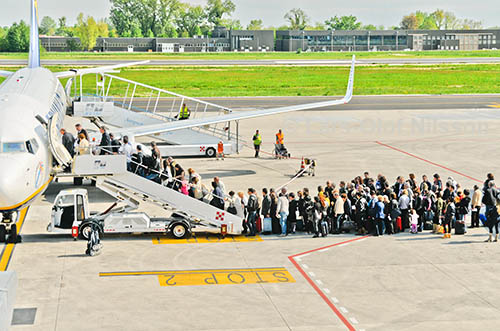 A queue of travellers waiting to embark on an aircraft at the airport of Treviso, Italy. The image illustrates the phrase 'afraid of'.