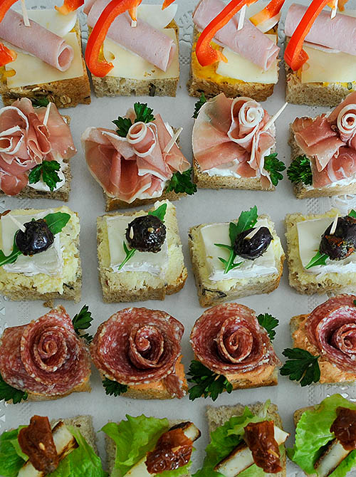 Rows of small canapés with soft cheese and olives, ham, salami, etc. The image is meant to illustrate Content or contents?