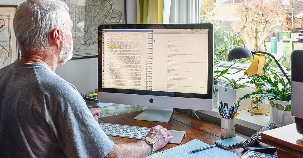 Man typing on a computer keyboard. The screen shows two documents. The image illustrates the use of the word experience as opposed to experiences.