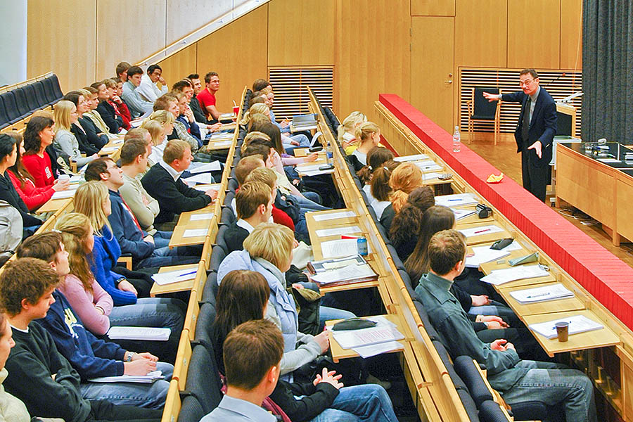 A speaker in front of his audience of students. The image illustrates the difference between connect to and connect with.