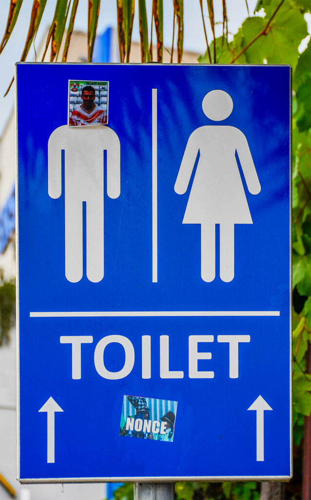 A sign pointing towards a toilet. The image illustrates various euphemisms such as restroom, lavatory, bathroom, etc.