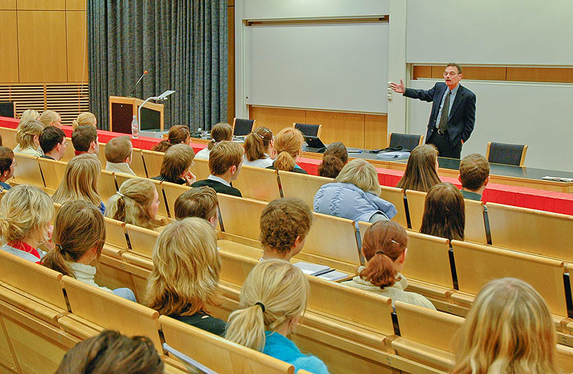 A lecturer in front of a group of students. The image illustrates the use of punctuation marks in quotations.