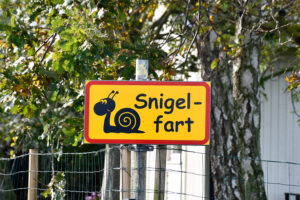 Traffic sign showing a snail and with the text 'at a snail's pace' in Swedish.